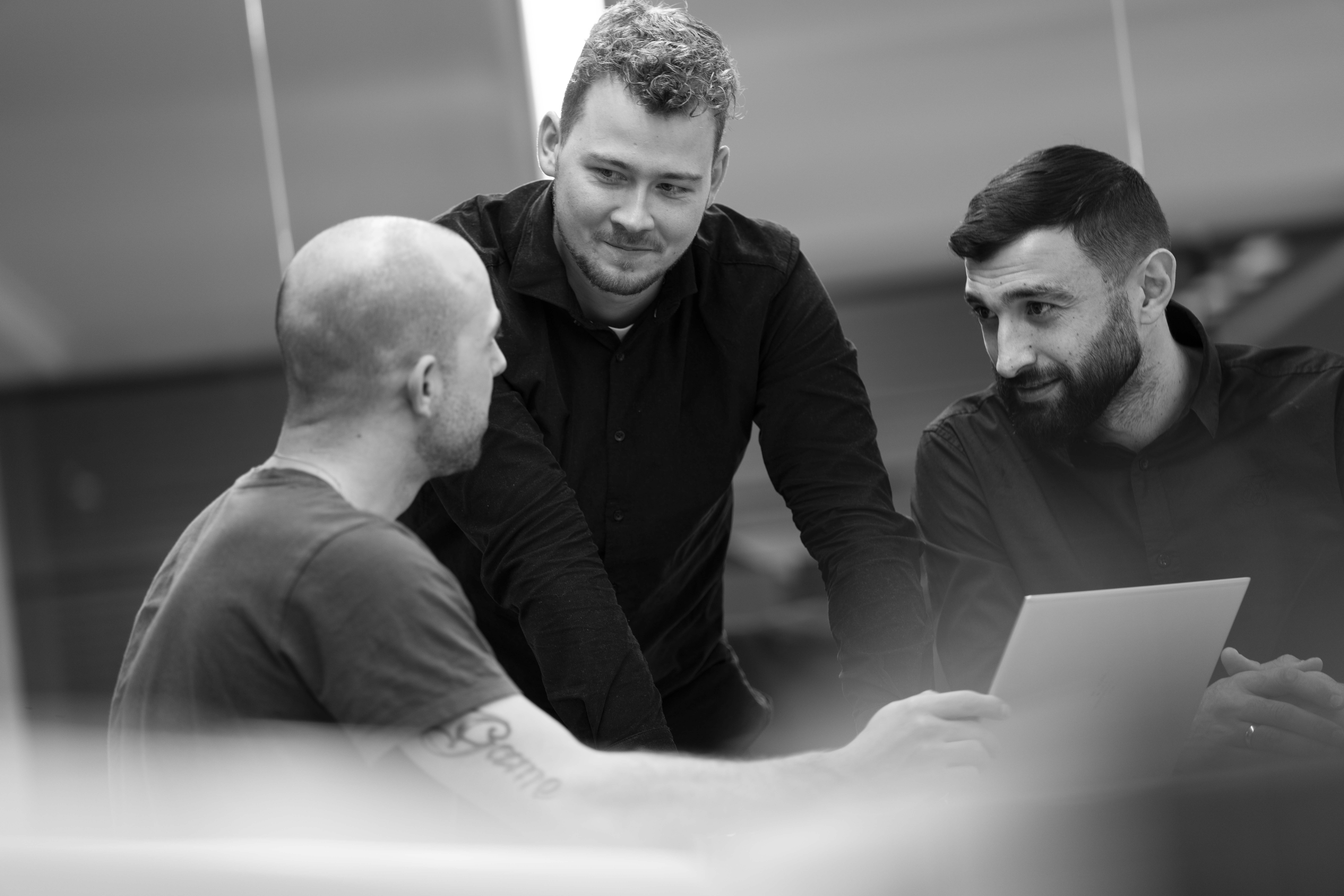 Black and white photo of three site managers in conversation.